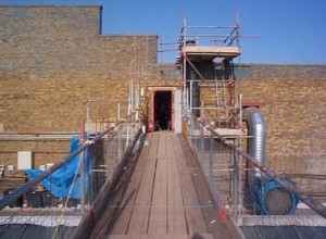 Scaffold walkway installed to remove reinforced concrete walls in atrium