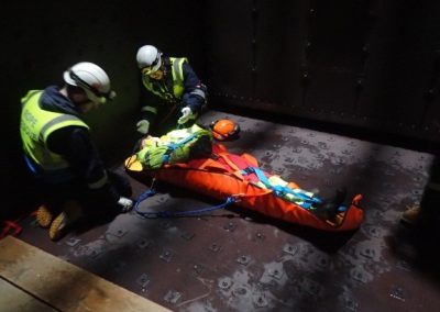 Injured person being secured into rescue stretcher for confined space rescue